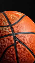 Close-up of a textured orange basketball with black seams showing signs of wear and tear against a dark background