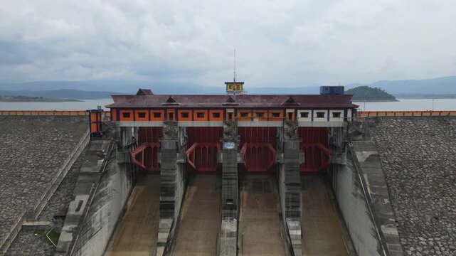 Aerial View of Dam Spillway Releasing Water with Reservoir Jatigede Indonesia and Mountains in Background 