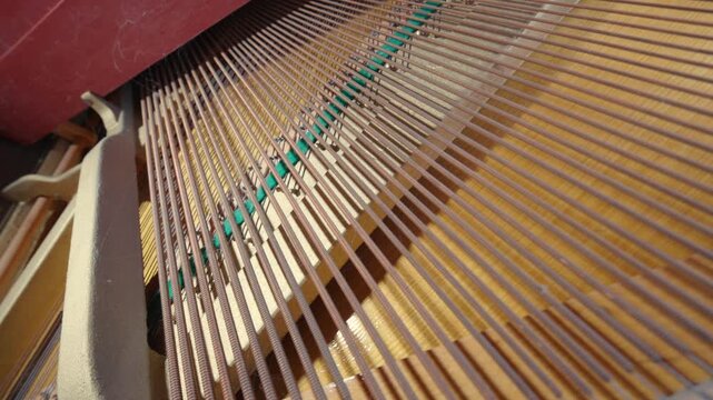 Upright Piano Internal Strings and Soundboard | Close-Up of Aged Musical Instrument Mechanism | Copper Wire Strings with Green Dampers Detail. Wide-Angle Bottom-Up View