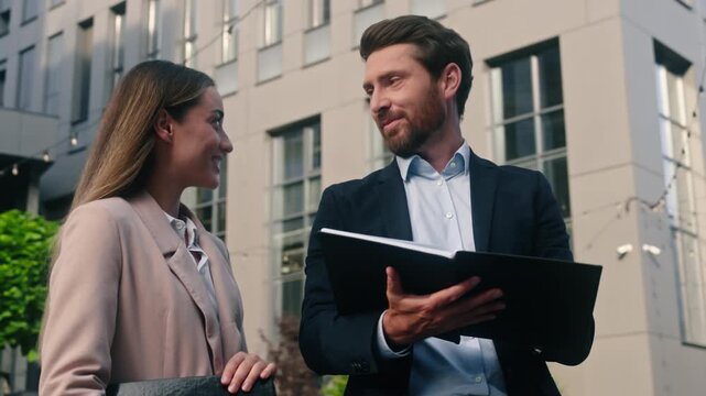 Two Caucasian business colleagues man woman in city discuss talking high five successful coworkers businessman male guy female girl businesswoman office building together work cooperation partnership