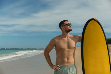Young man stands confidently on the shore near the ocean © Atlas
