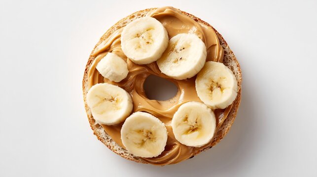 Fresh bagel topped with creamy peanut butter and sliced ripe bananas, overhead view