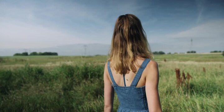 Woman in a blue dress standing in a field of tall grass