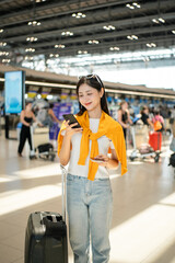 Happy young asian woman traveler holding boarding pass ticket, passport and smartphone at the...
