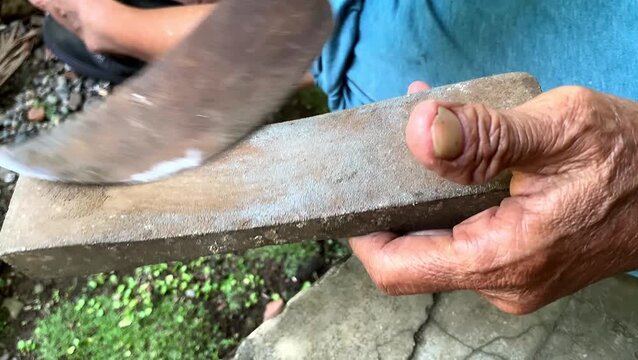 Senior hands sharpening traditional knife on grinding stone. traditional tools.