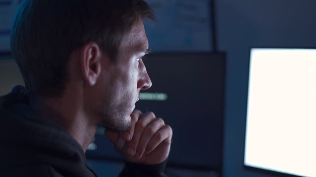 Software developer working at computer with headset in dark office coding environment