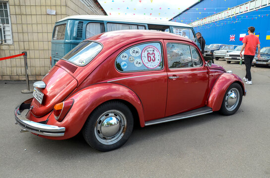  Iconic Volkswagen Type 1, known worldwide as the Beetle. The car is painted in a deep dark red, emphasizing its characteristic rounded shapes and retro aesthetic