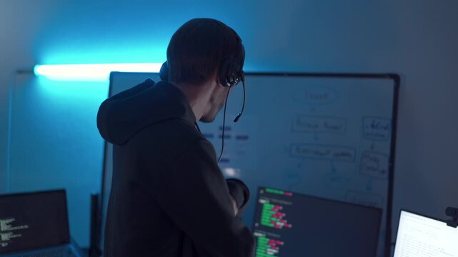 Programmer discussing software development in technology office with multiple monitors