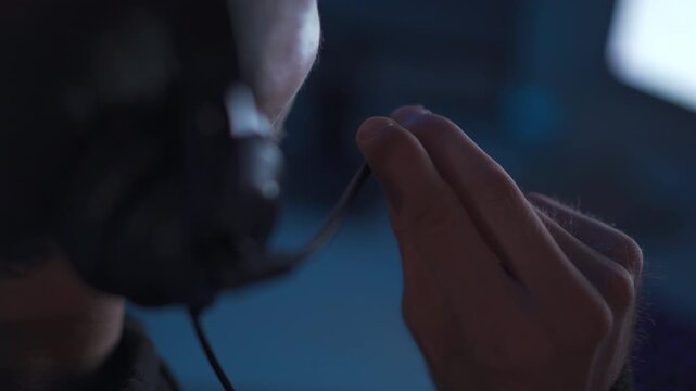 Close up of programmer wearing headset while monitoring code on computer screens