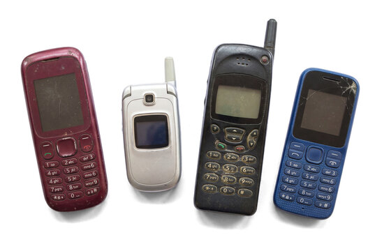 A collection of four distinct, aged mobile phones, representing early generations of wireless communication technology.