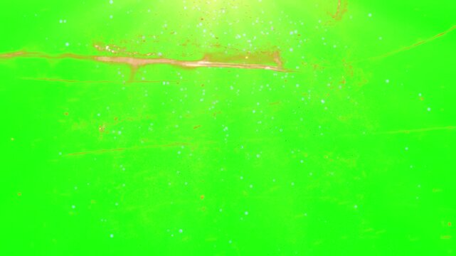 A video showcasing a green screen with a bright light shining down on two small objects