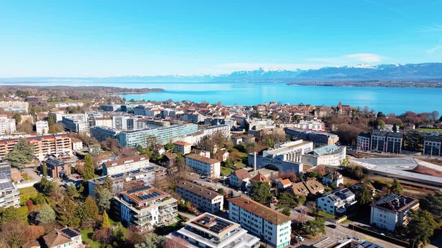 Parallax drone shot of Nyon cityscape and downtown during the day with Lake Geneva in Canton of Vaud, Switzerland