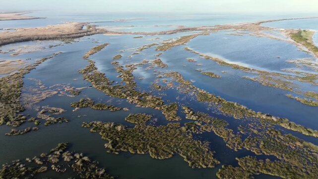 Cinematic high-angle drone shot of the protected Amvrakikos Gulf in Greece. Breathtaking view of intricate water channels, marshes and lagoons reflecting the soft daylight.