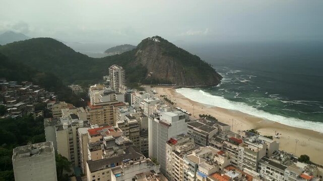 Copacabana city buildings and Pedra do Leme surrounded by ocean on a cloudy winter day. Upward tilting aerial glide recorded on 4K Apple ProRes 422.