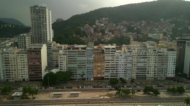 Forward aerial glide from Copacabana beach, approaching city buildings and Babilonia favela during a cloudy winter morning. Recorded at 4K Apple ProRes 422.