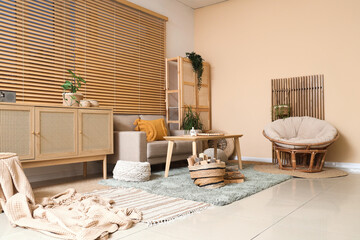 Naklejka premium Interior of living room with sofa, armchair, coffee table, commode, closet and firewood near window