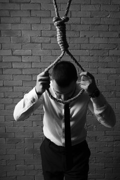 Businessman going to hang himself on brick background. International Stress Awareness Week