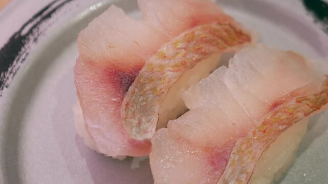 Fresh white fish nigiri sushi with skin-on snapper or sea bream on ceramic plate, Japanese traditional cuisine