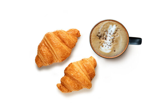 Cup of hot latte art coffee with coffee beans and two golden crispy croissants. Isolated on white background.