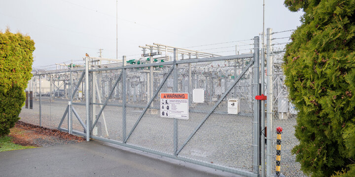 Electrical substation gate with warning sign and barbed wire fence