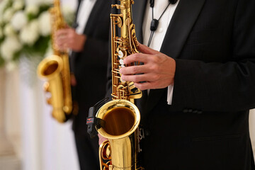 Obraz premium Jazz Day Man in black tuxedo playing golden saxophone at formal event music musician