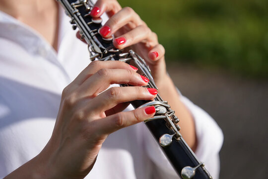 Jazz Day Woman's hands with red nails playing a black clarinet outdoors image