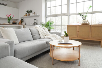 Interior of modern studio apartment with sofa, table and kitchen counters