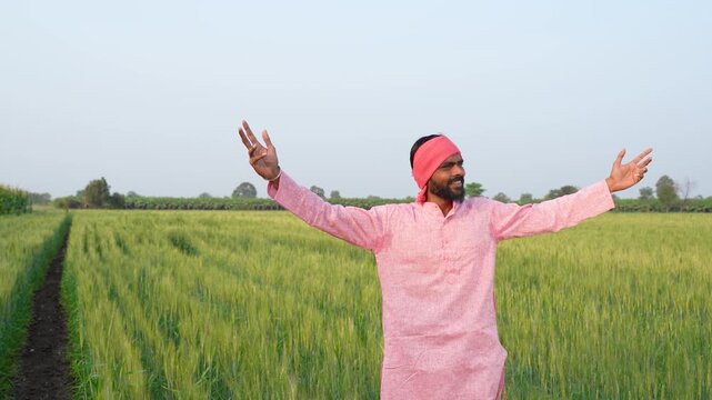 Young indian farmer standing at wheat agriculture field	
