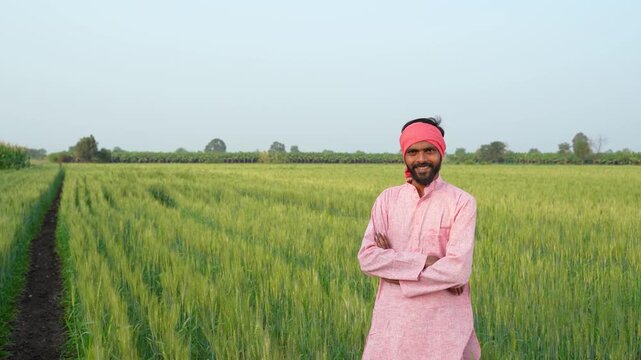 Young indian farmer standing at wheat agriculture field	