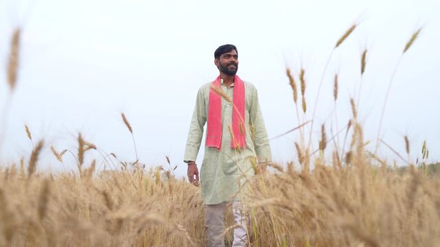 Young Indian farmer standing at wheat agriculture field 