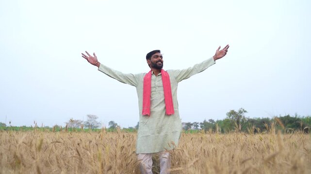Young Indian farmer standing at wheat agriculture field 