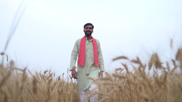 Young Indian farmer standing at wheat agriculture field 