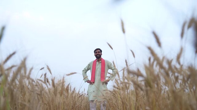 Young Indian farmer standing at wheat agriculture field 