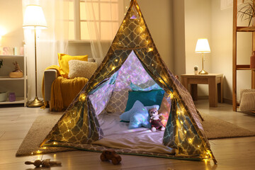 Interior of children's room with play tent, sofa and glowing lamps at night © Pixel-Shot