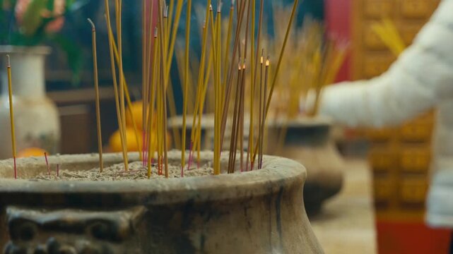 Chinese people lighting incense sticks and praying inside Man Mo Temple in downtown Hong Kong, showing traditional rituals and spiritual practices.