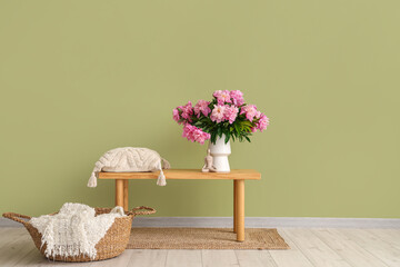 Naklejka premium Vase with peonies flowers and pillow on bench in stylish living room