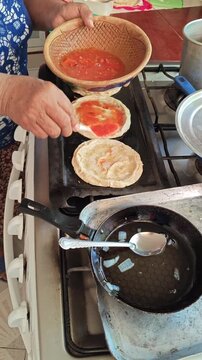 Pouring red sauce on mexican picadas corn dough