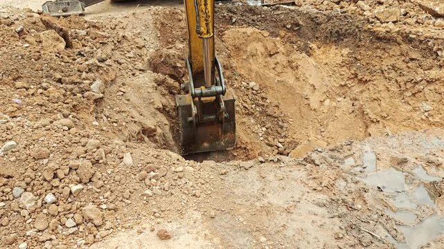 Excavator bucket removing soil from a deep pit