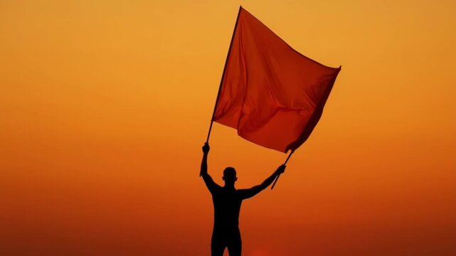 Silhouette of a Person Holding a Large Saffron Flag During Sunset with Vibrant Sky and Cultural Significance