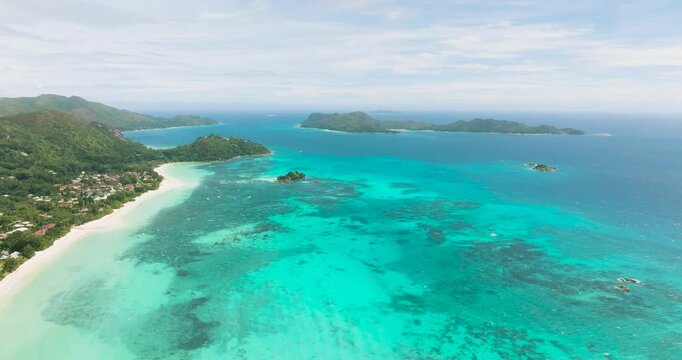 Sweeping panoramic view of turquoise waters with green hills and lush forests along the coast. Anse Volbert. Seychelles, Praslin.