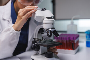 Scientist examining sample using microscope in laboratory