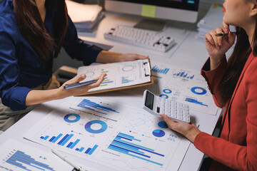 Business women analyzing data charts for financial planning © Phimwilai
