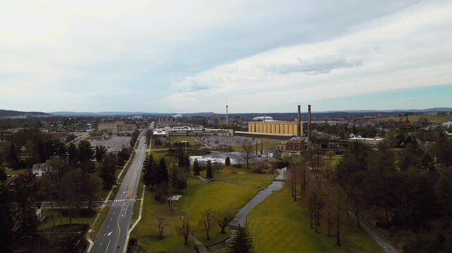 A cinematic aerial drone shot of the historic red-brick smokestacks featuring the Hershey name, overlooking the industrial landscape of Chocolate Town, USA.