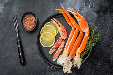Premium alaskan king crab seafood with lemon and thyme on black dish dark stone surface restaurant style copy space © Mironov