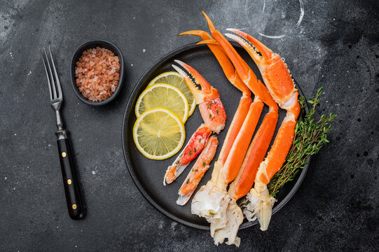 Premium alaskan king crab seafood with lemon and thyme on black dish dark stone surface restaurant style copy space