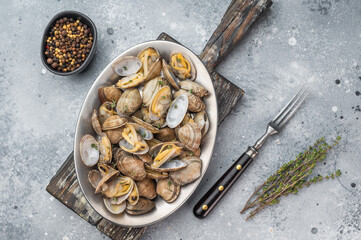 Prepared vongole mollusks served in oval bowl on gray textured background. Clean seafood composition. © Mironov