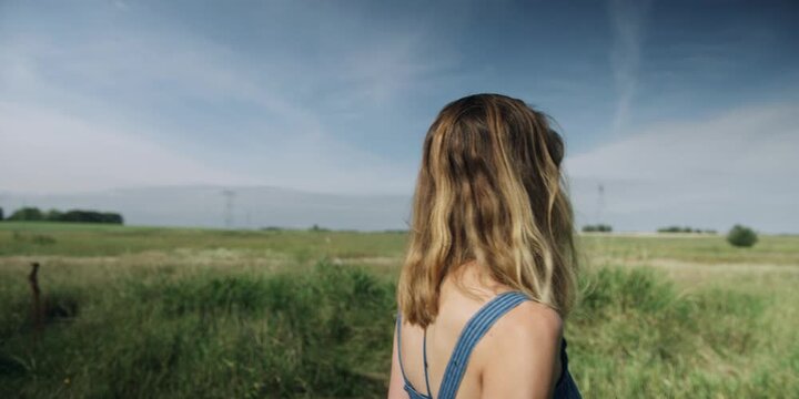 Woman standing in a meadow under a wide blue sky