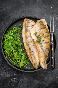 Cooked zander fillets, also known as walleye or pike perch, seared and plated with greens.