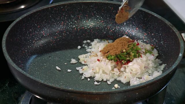 Chef Adding Aromatic Cumin Powder to Saut&eacute;ed Onions for a Flavorful Base