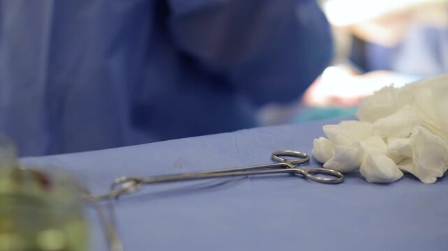 Surgical instruments, including forceps and sterile gauze, arranged on blue draping in an operating room. The scene evokes feelings of hope and seriousness, essential for complex medical procedures.